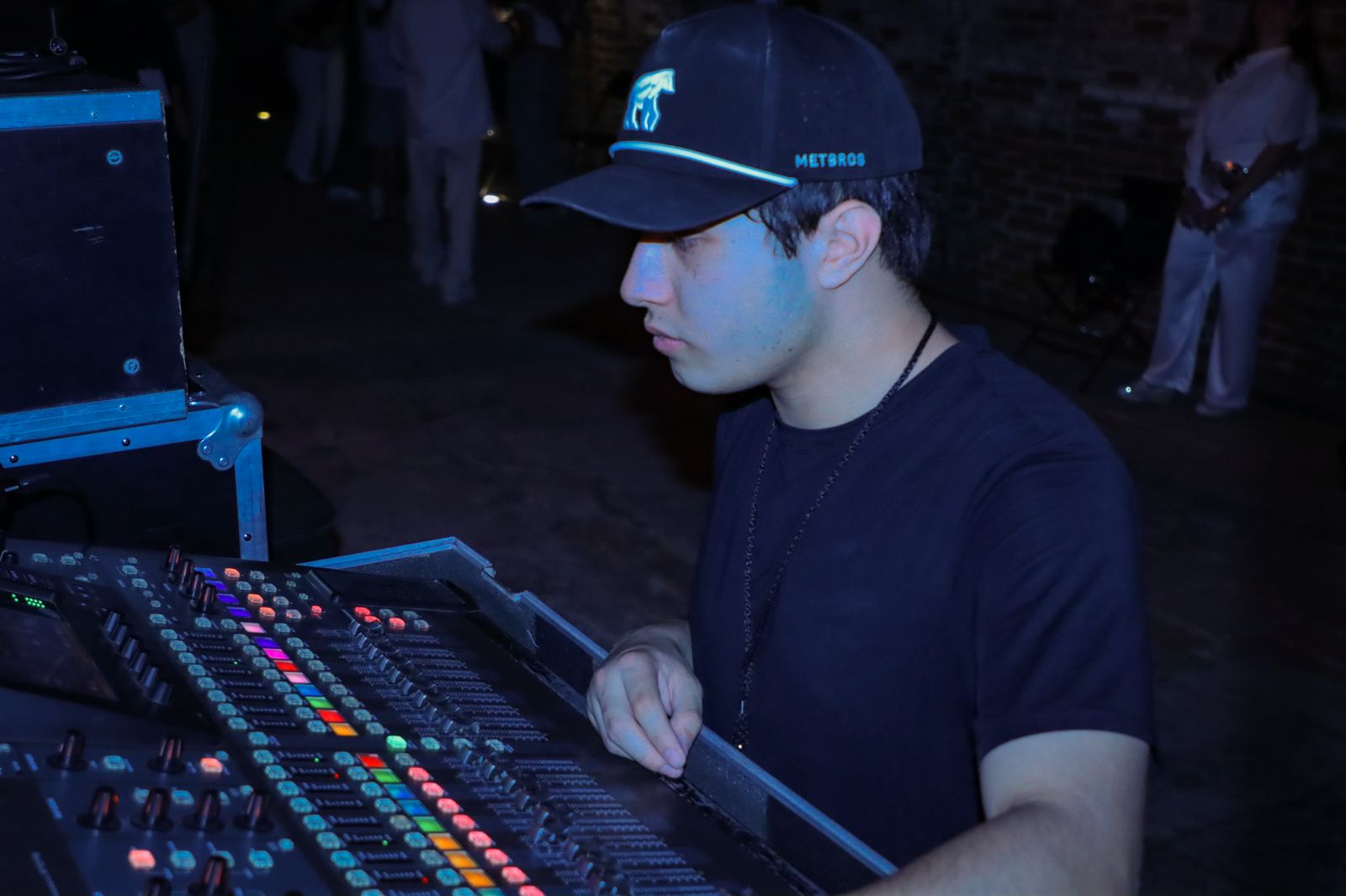 Nova, audio engineer, working at a digital mixing console in a dark studio
